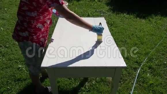 草地上花园里白色老式木桌上的油漆视频的预览图