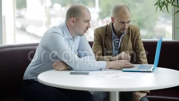 两个商人在办公室开会时用笔记本电脑视频的预览图