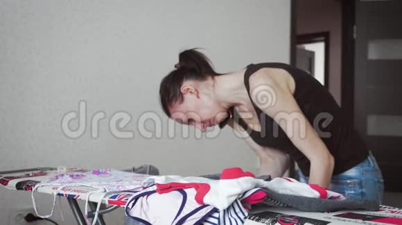 女士在家洗衣服后用熨斗在熨衣板上熨烫衣服视频的预览图