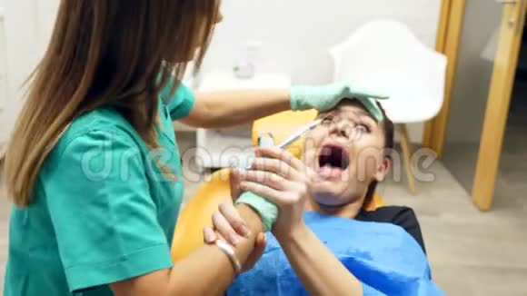 一位女牙医挣扎着给一位年轻的女士麻醉病人因为大针而害怕视频的预览图