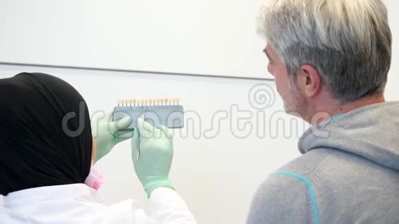 一位戴头巾的女牙医咨询一位牙齿颜色为哪种颜色的病人视频的预览图