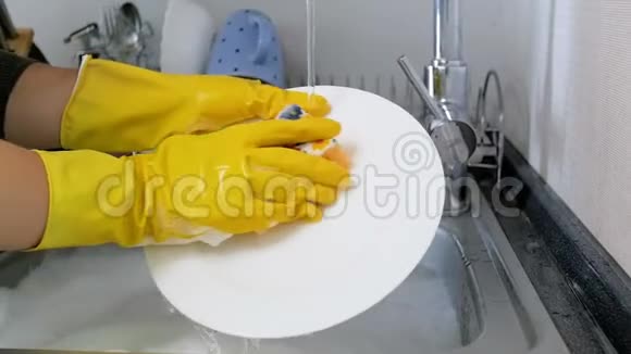 家庭主妇戴黄色橡胶手套在厨房水槽洗碗的特写慢镜头视频的预览图