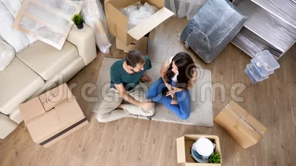 顶景年轻夫妇坐在他们新公寓的地板上视频的预览图