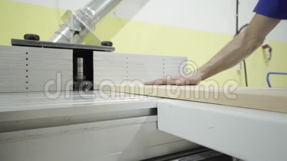 工人的特写在木工机械上放木工板行动工人在手套上加工木板视频的预览图