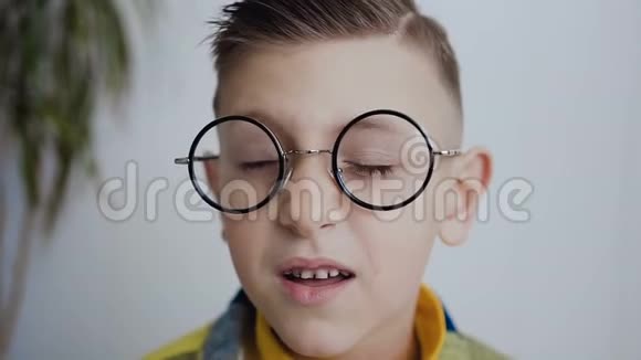 一个眼睛斜视视力不好的小男孩的面部特写他戴着眼镜看得更好这就是视频的预览图