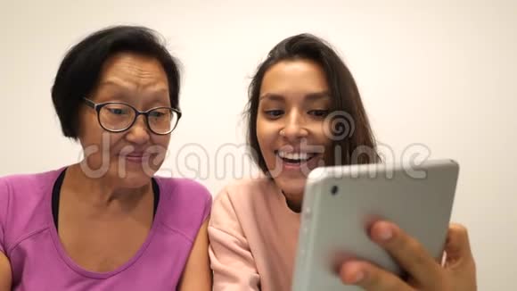 亚洲退休的母亲和小女儿用平板电脑制作有趣的自拍照片4k视频的预览图