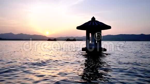 中国杭州西湖美丽的日落景观橙色黄昏的天空和宁静的水与传统的亭子视频的预览图