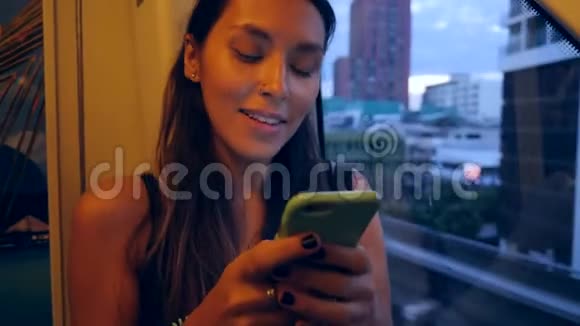 在地铁梅托列车上使用移动电话的嬉皮士女孩背景上有夜间城市窗口4K视频的预览图
