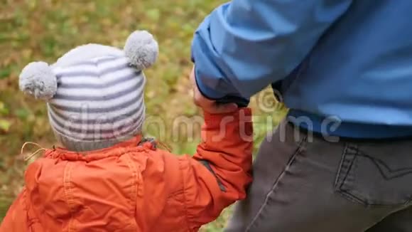 一位年轻的父亲和孩子一起在公园里散步父亲牵着儿子手温柔和拥抱她心爱的父亲视频的预览图