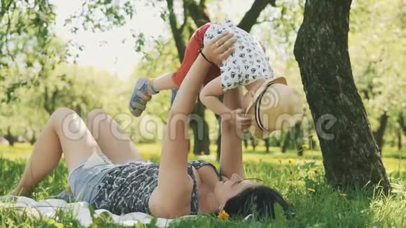 快乐的微笑妈妈和小儿子在大树下野餐家庭概念视频的预览图
