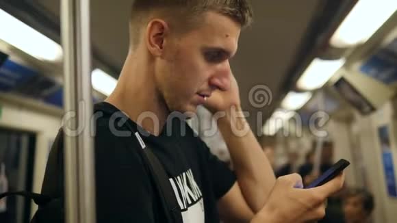 年轻的白种人坐地铁列车用手机发短信4K视频的预览图