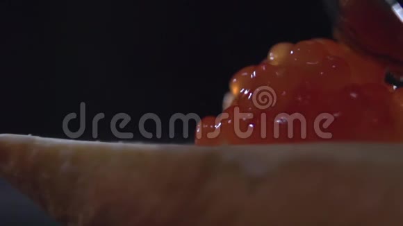 在三明治上涂上红色鱼子酱的勺子特写视频的预览图