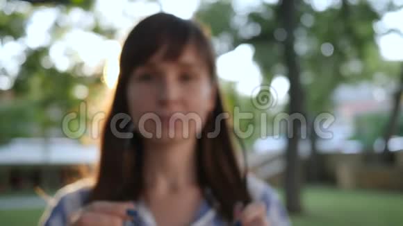 女孩在户外公园戴上眼镜对着镜头微笑视频的预览图