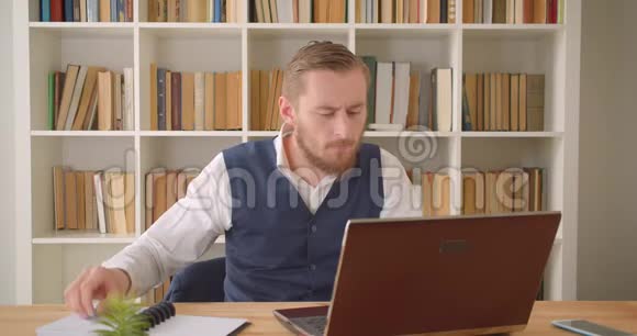 年轻白种人商人使用笔记本电脑并在室内记录工作场所的特写照片视频的预览图