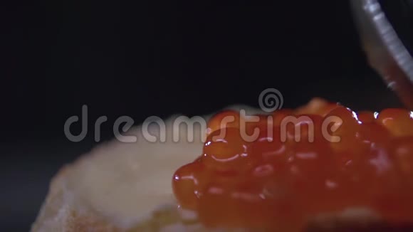 勺子在面包上的黄油上涂上红色的鱼子酱视频的预览图