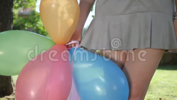 戴着牙套的女孩的肖像在公园的背光处放着五颜六色的充气气球特写镜头微笑视频的预览图