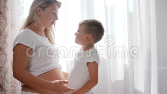 幸运的孩子拥抱未来的母亲在自然光的房间里大肚子视频的预览图