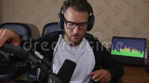 戴耳机的微笑收音机主持人坐在椅子上用麦克风讲话听音乐视频的预览图
