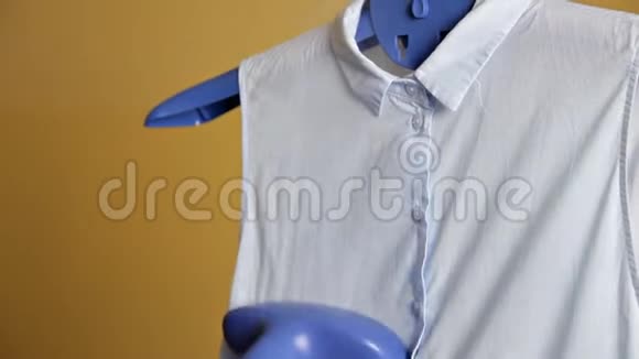 年轻女孩用蒸汽系统熨烫衣服蒸汽蓝色衬衫在家视频的预览图