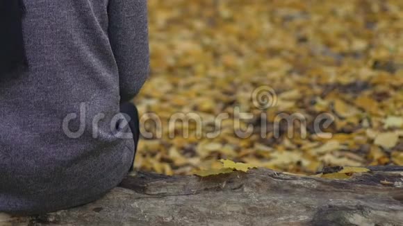 灰色的男性坐在公园后景的长凳上秋天的忧郁悲伤的心情视频的预览图