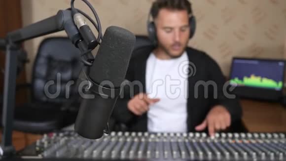 在无线电演播室音频调音台前戴耳机的人进入无聚焦背景视频的预览图