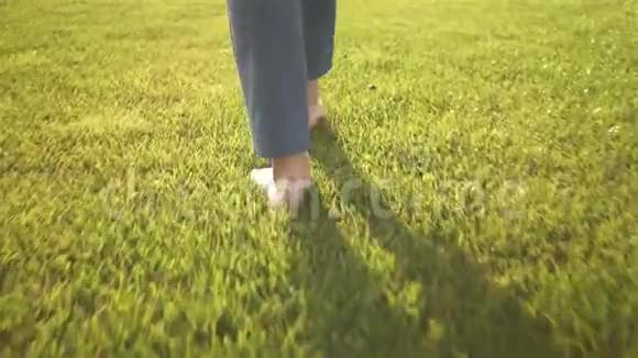 女人光着脚走在草地上的后景视频的预览图