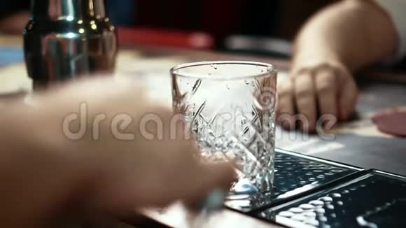 在时尚的酒吧里用冰块将威士忌酒杯加满动作缓慢视频的预览图