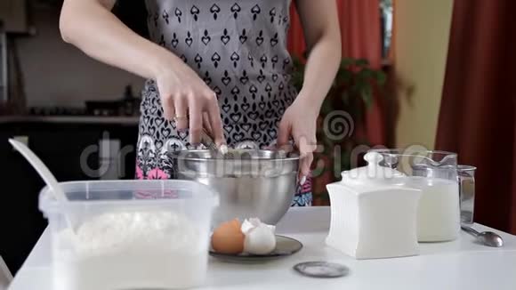 厨房里的女孩在银碗里摇着烘焙所需的原料烹饪和烘焙的概念视频的预览图