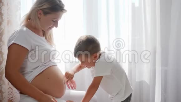 小男孩在室内沿着怀孕女性的腹部抚触手指视频的预览图