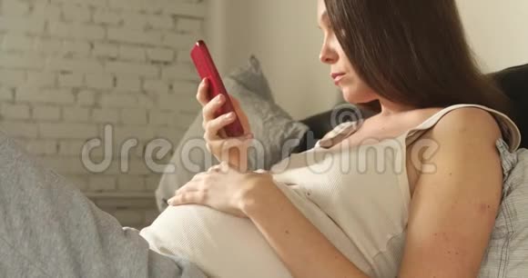 孕妇在家里使用智能手机视频的预览图