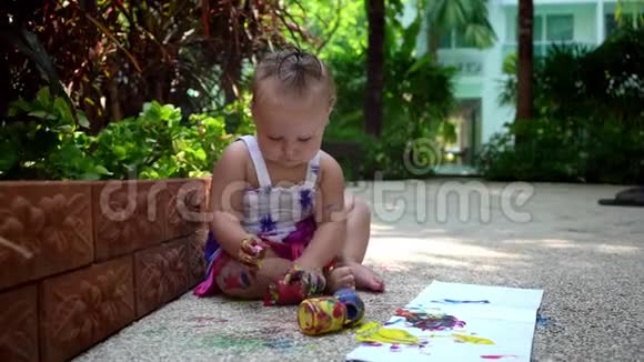 漂亮的小女孩用手指在一张白纸上画画在幼儿园或视频的预览图