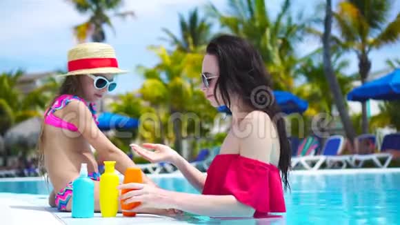 年轻的妈妈在游泳池里给孩子的鼻子涂上防晒霜防止紫外线辐射的概念视频的预览图