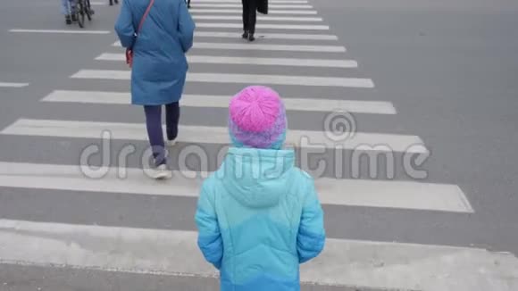 年轻女孩通过人行横道过马路穿蓝色夹克的女孩放学回家视频的预览图