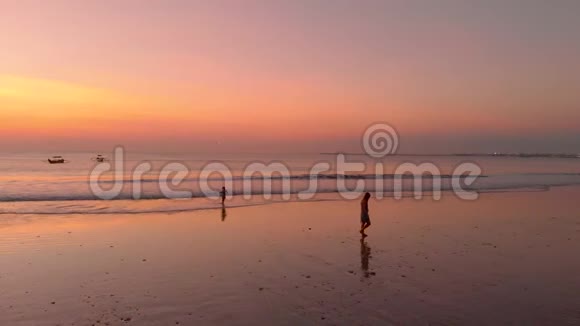 日落时分一名妇女和她的儿子在海边散步视频的预览图
