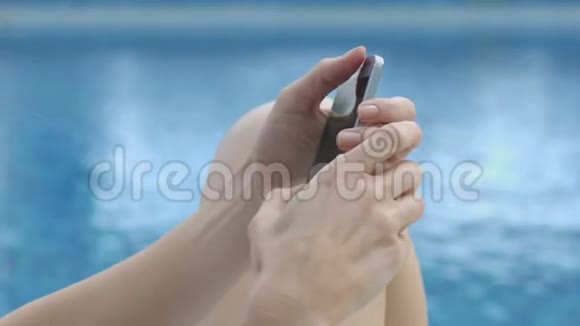 坐在水边的女人在智能手机上写留言在线通信视频的预览图