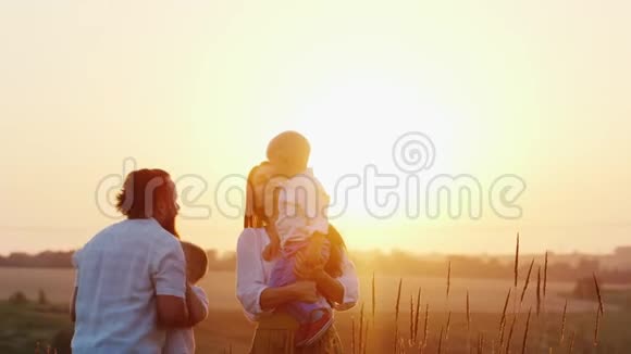 有两个孩子在大自然中玩耍的年轻家庭日落时分视频的预览图