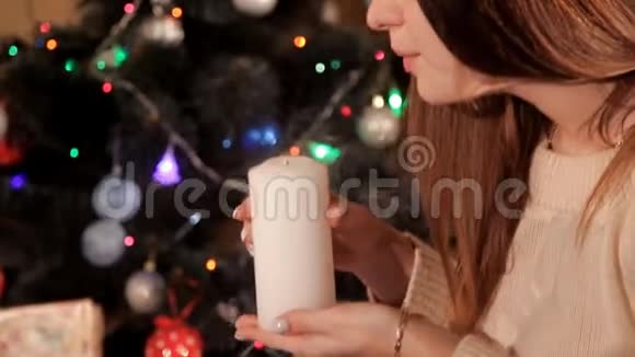 在圣诞节圣诞树附近的环境中女孩吹灭了蜡烛视频的预览图