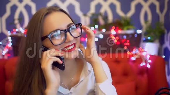 幸福的女人在她的智能手机上说话智能手机女人在咖啡馆里打电话笑年轻女性视频的预览图
