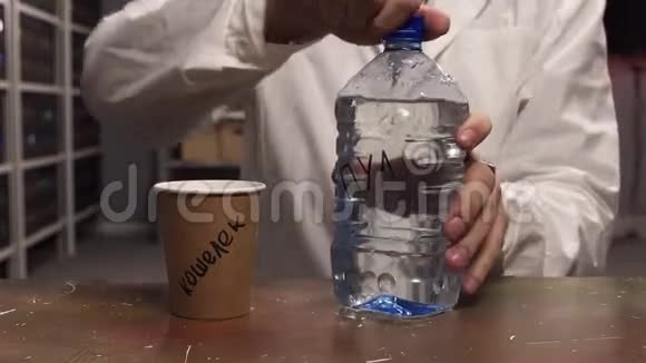 穿着白色实验服的人把水从塑料瓶倒入棕色纸杯视频的预览图
