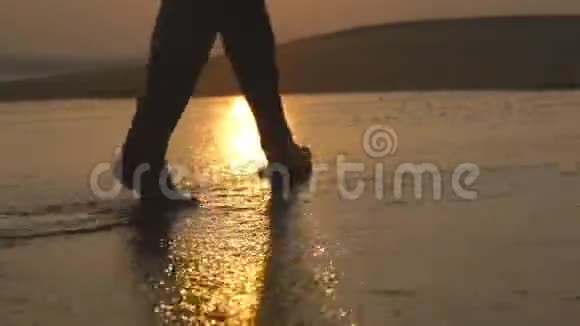 日出时年轻女子沿着海边的腿日落时女性赤脚在海边行走女孩视频的预览图