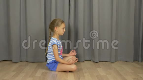 一个小女孩正在冥想坐在室内客厅的地板上视频的预览图