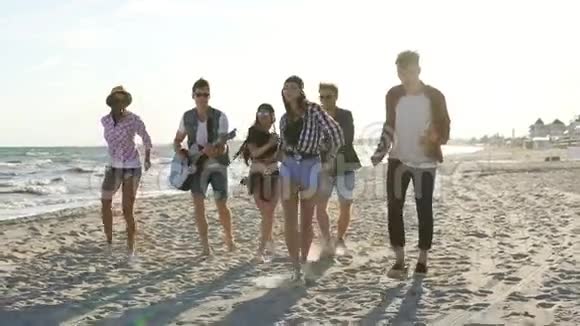 男孩和女孩一起鼓掌一起跳舞弹吉他在水边的沙滩上唱歌视频的预览图