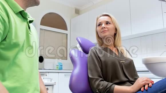 4k镜头快乐微笑的女人坐在牙医椅上和医生握手视频的预览图