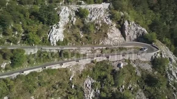 骑着摩托车和一辆汽车在华丽茂盛的森林山坡上驰骋穿过起伏的道路视频的预览图