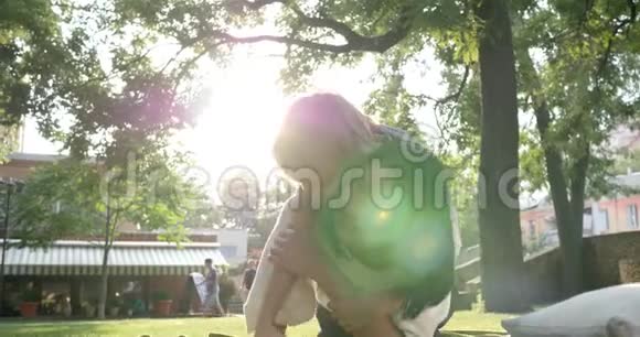 一家人年轻的母亲带着快乐的孩子微笑躺在绿色的草地上背光视频的预览图