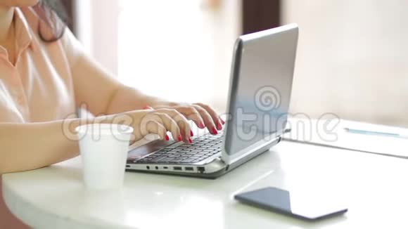 一个女人坐在咖啡馆里喝咖啡用笔记本电脑工作慢点视频的预览图