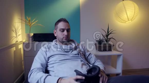 穿着懒包的男人在家里玩虚拟现实游戏视频的预览图