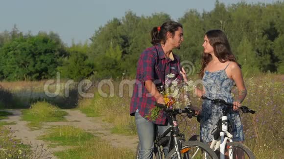 一对骑着自行车在田间道路上的夫妇视频的预览图