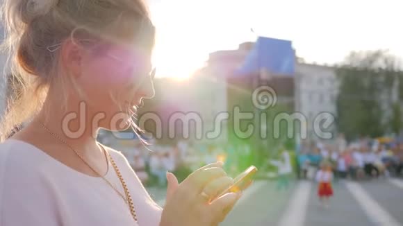 戴着太阳镜的可爱女孩在阳光下手挽着手机视频的预览图