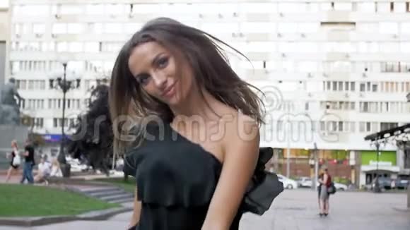 慢镜头视频美丽的黑发女人穿着黑色衣服走在街上看着镜头视频的预览图